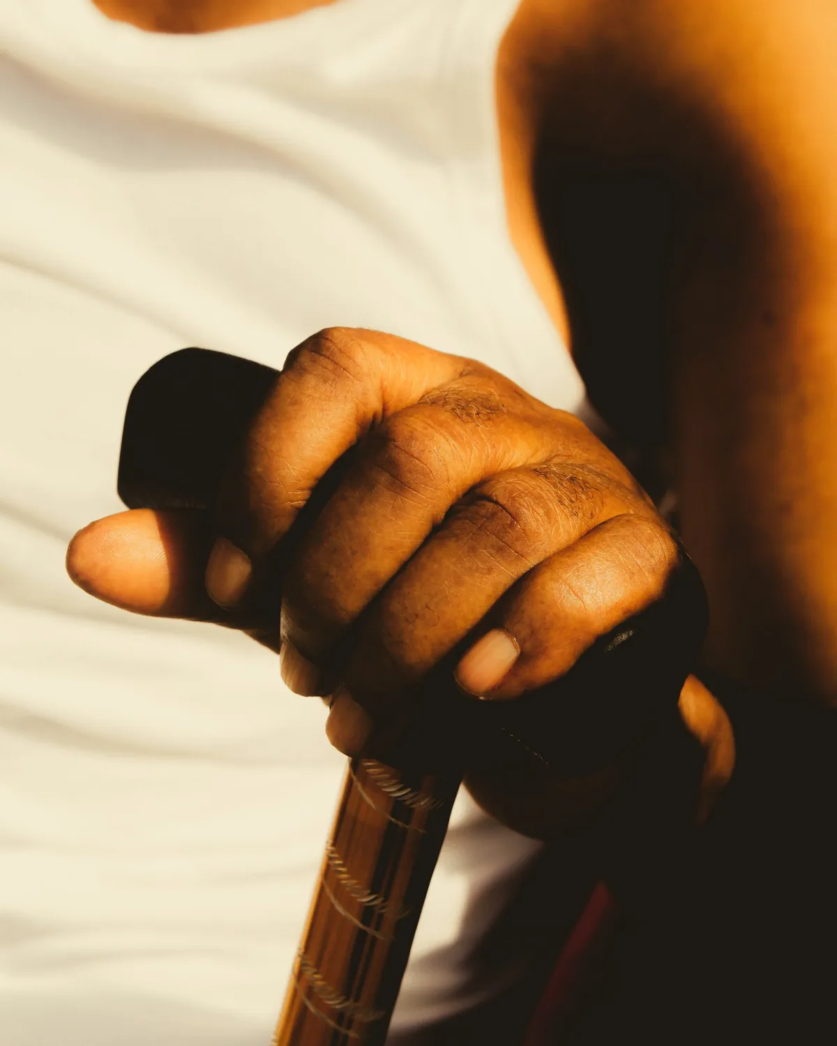 Close-up of a hand resting on the handle of a walking cane, lit by warm daylight
