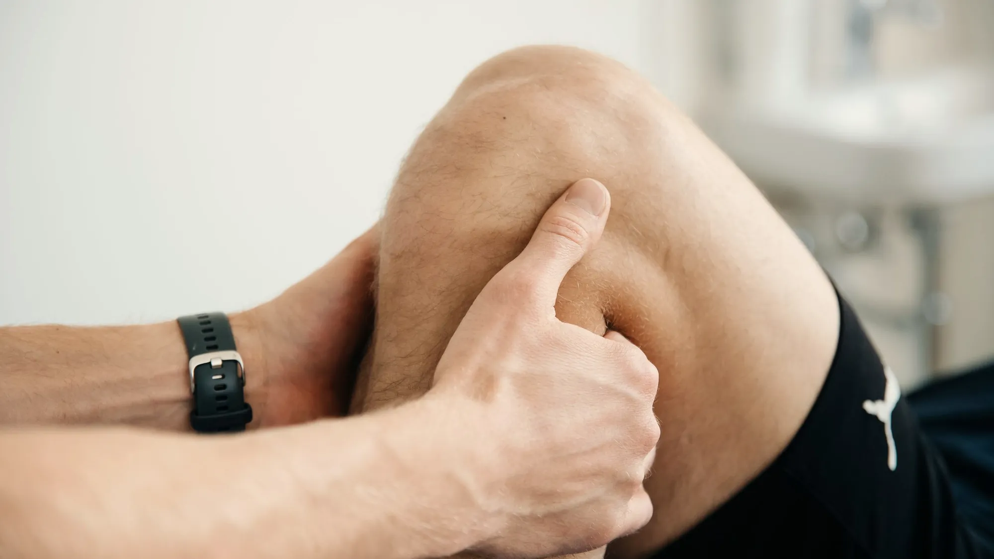Close-up of a therapist's hands supporting and testing a bent knee