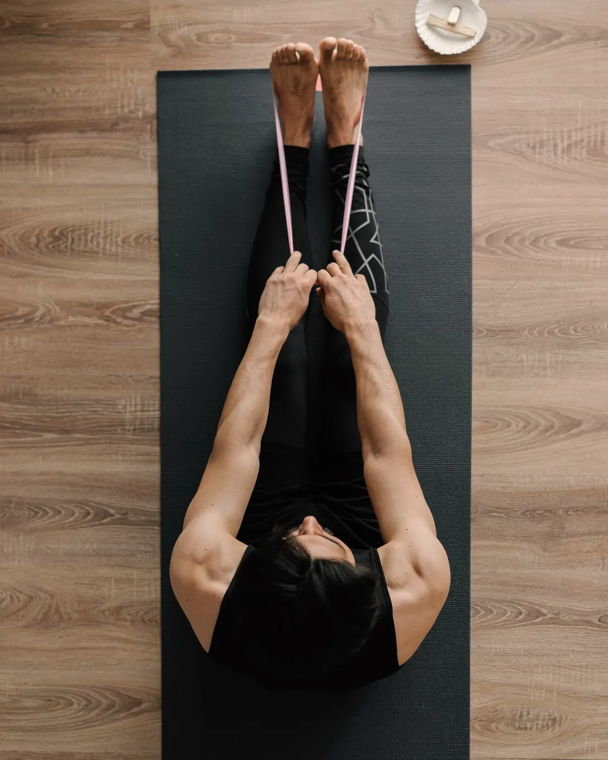 Overhead view of a person on a floor mat working through a stretch with a resistance band