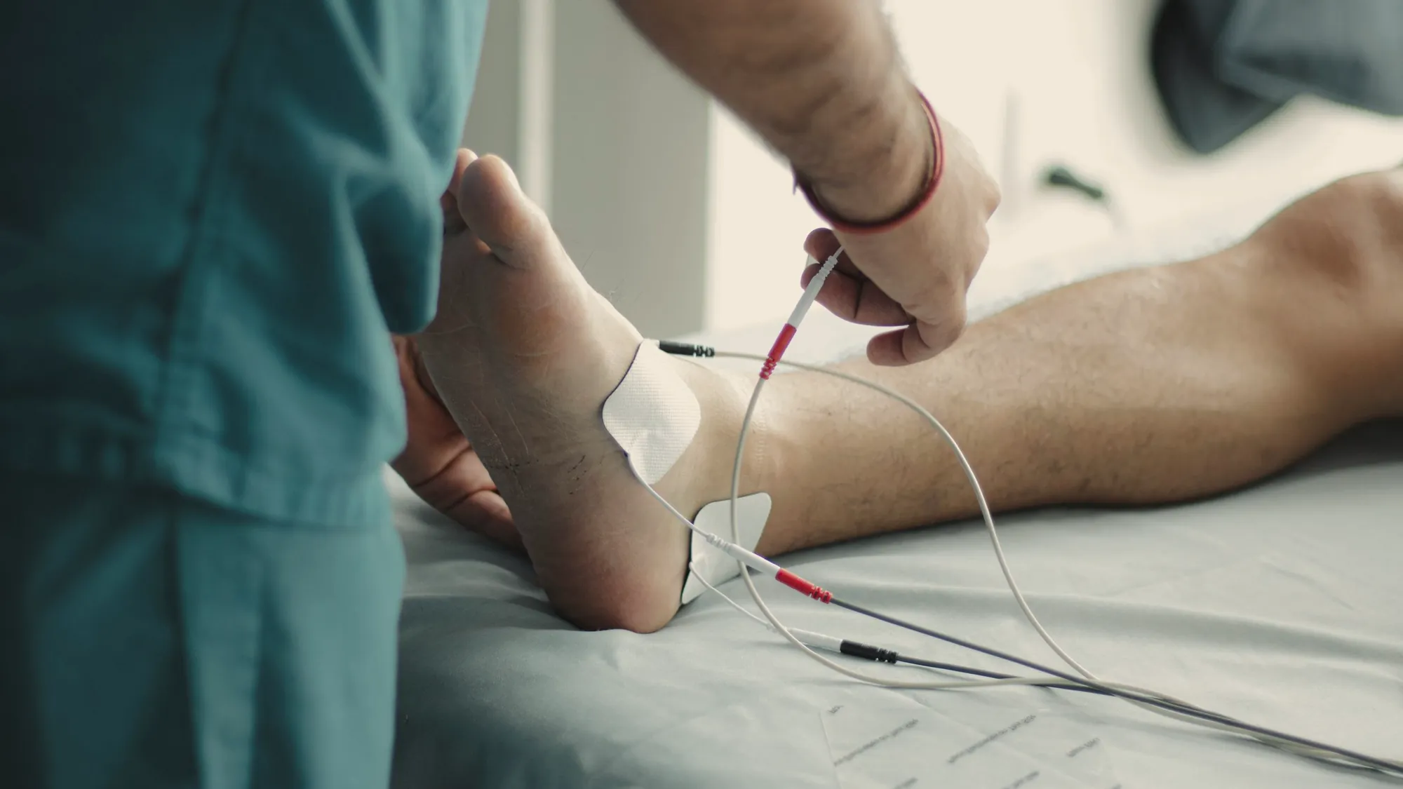 Close-up of a clinician placing measurement electrodes on a patient's ankle and foot
