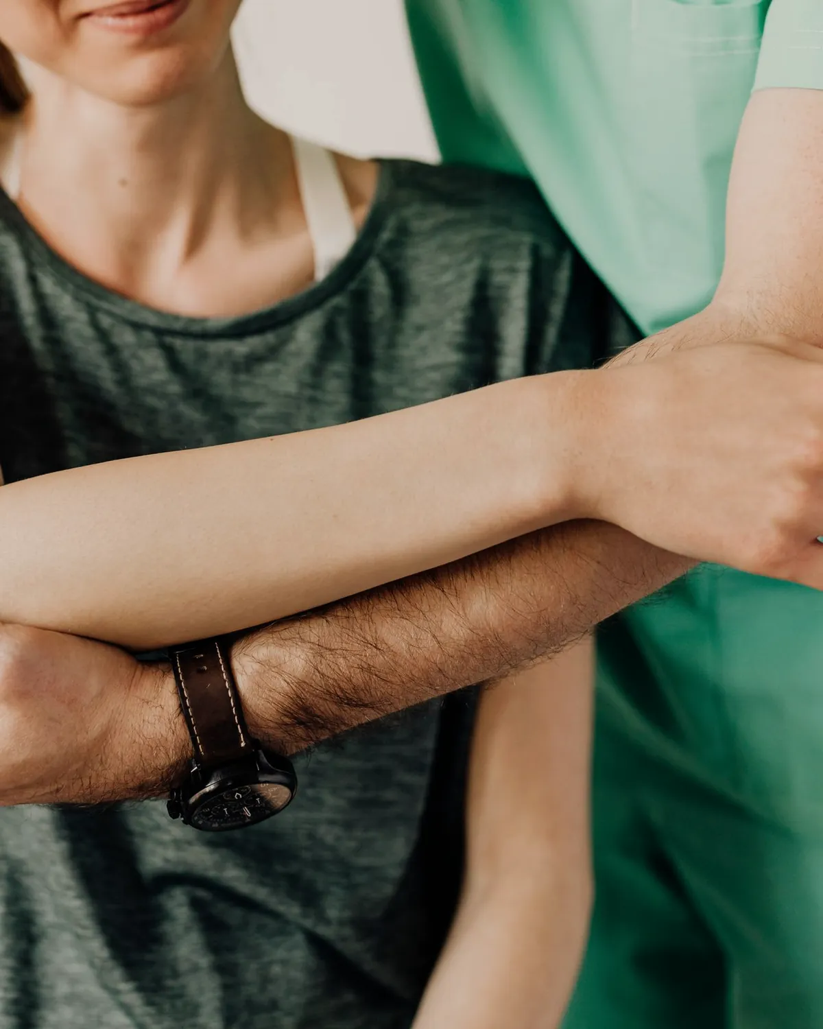 A clinician's hands supporting a person's forearm and elbow through a movement